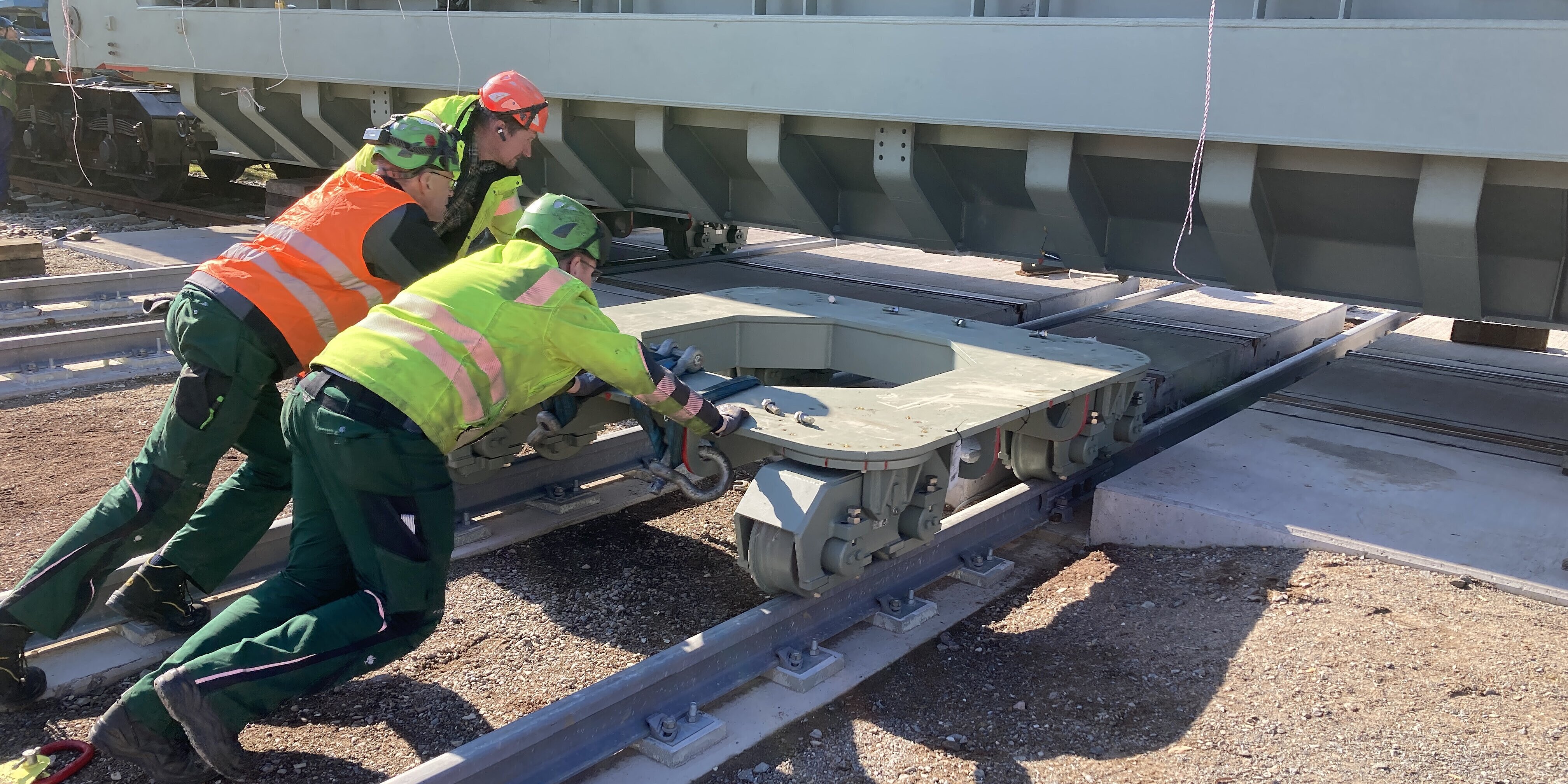 Fachkräfte manövrieren das Fahrwerk unter den Transformator, um den Richtungswechsel für den Quer- und Längsverzug vorzubereiten 